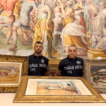 Italian police in black 'Carabineiri' clothing standing with three gold-framed paintings in front of a large portrait